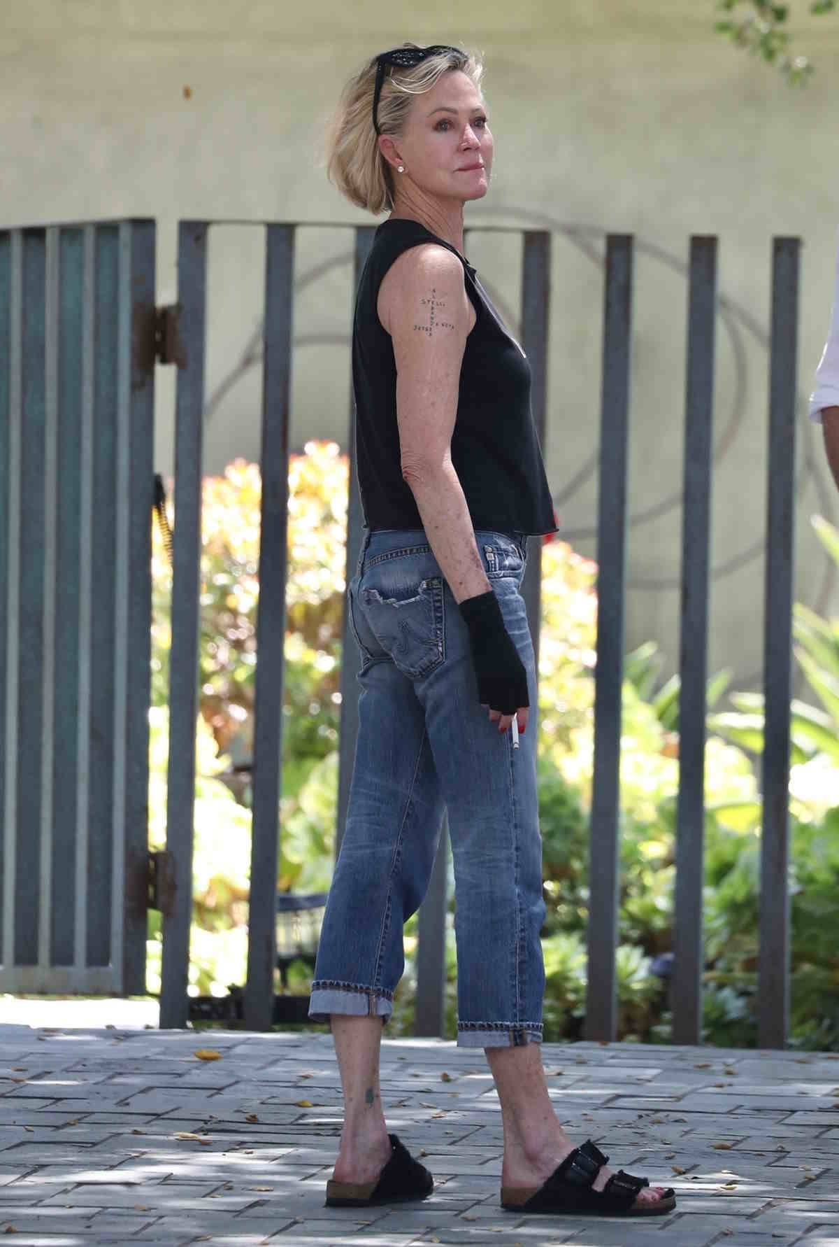 Melanie Griffith w jeansowych spodniach 7/8 z wywiniętą nogawką i Birkenstockach.