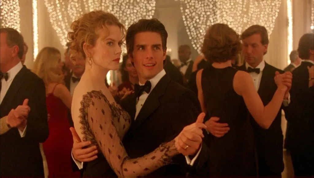 Nicole Kidman i Tom Cruise tańczą w eleganckiej scenerii z filmu „Oczy szeroko zamknięte”, w atmosferze napięcia.