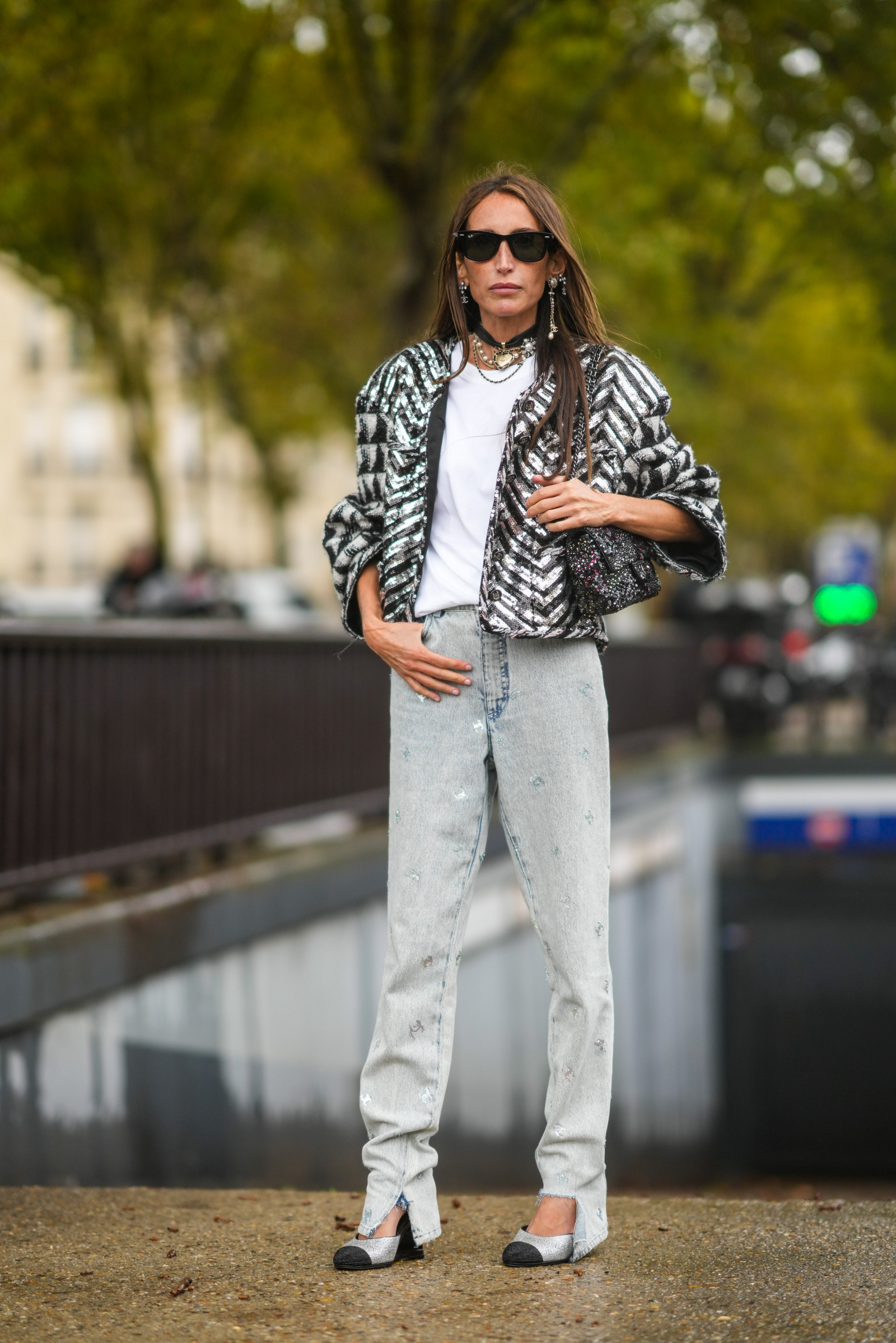 It-girl w jeansach Chanel i białym T-shircie, ubrana w kurtkę z cekinami, pozująca na ulicy w Paryżu.