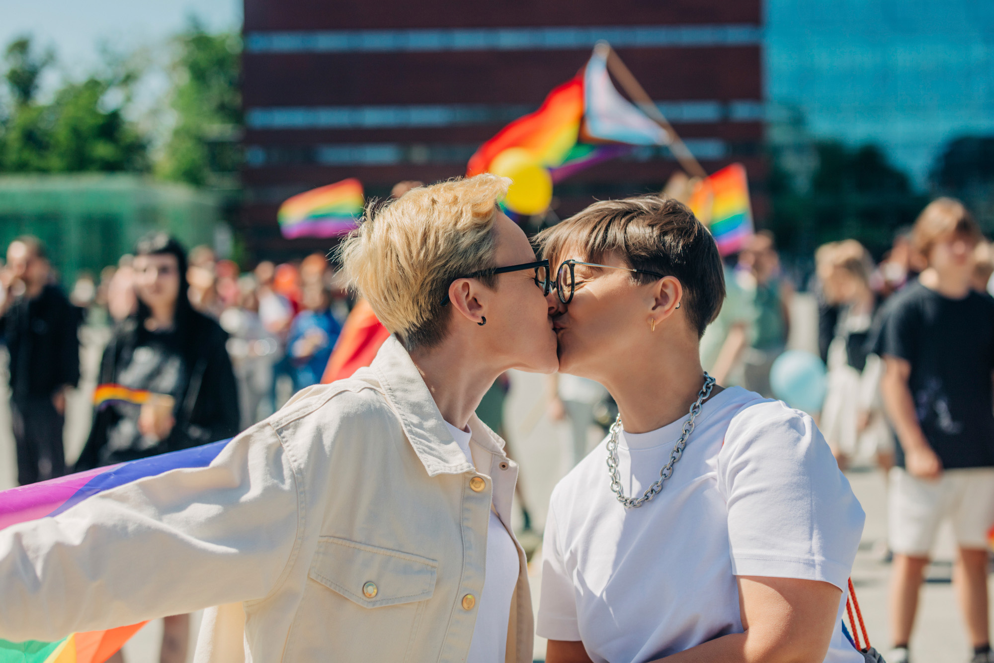 Para LGBT+ całuje się  wśród tęczowych flag.