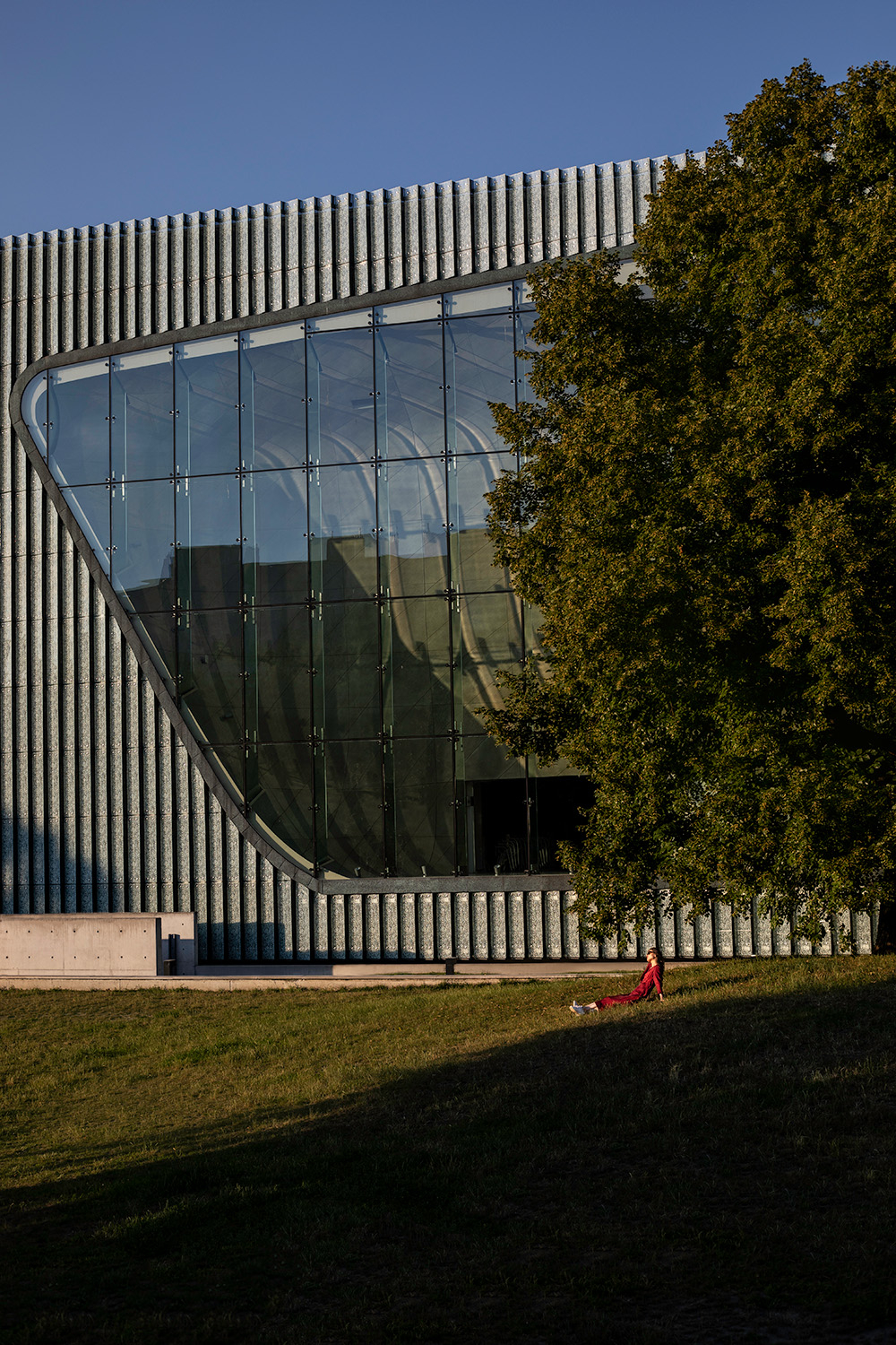 Muzeum Polin w Warszawie z charakterystyczną szklaną fasadą i zielonym terenem wokół.