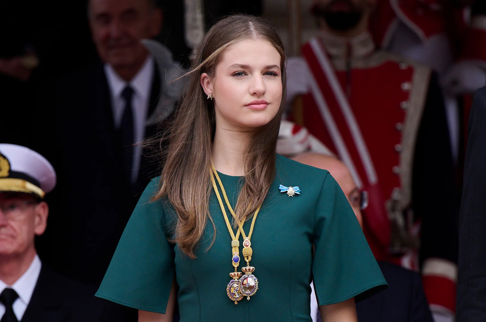 Księżniczka Eleonora z Hiszpanii w zielonej sukience, z medalami zawieszonymi na szyi, podczas ceremonii publicznej.