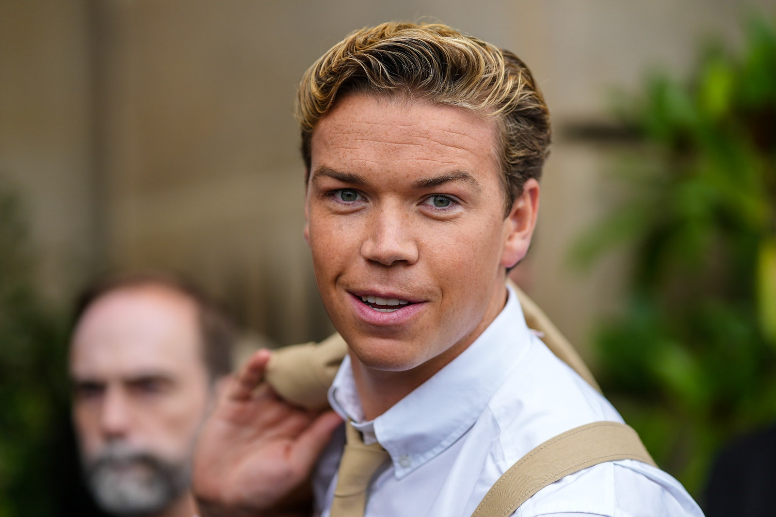 Will Poulter w jasnej koszuli z marynarką przewieszoną przez ramię