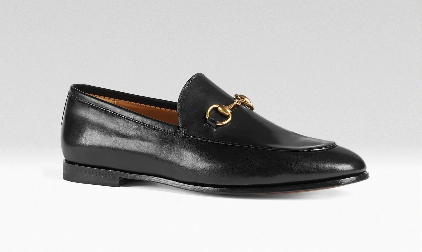 Czarne mokasyny Gucci z połyskującej skóry, zdobione złotym detalem. Elegancki i klasyczny design.