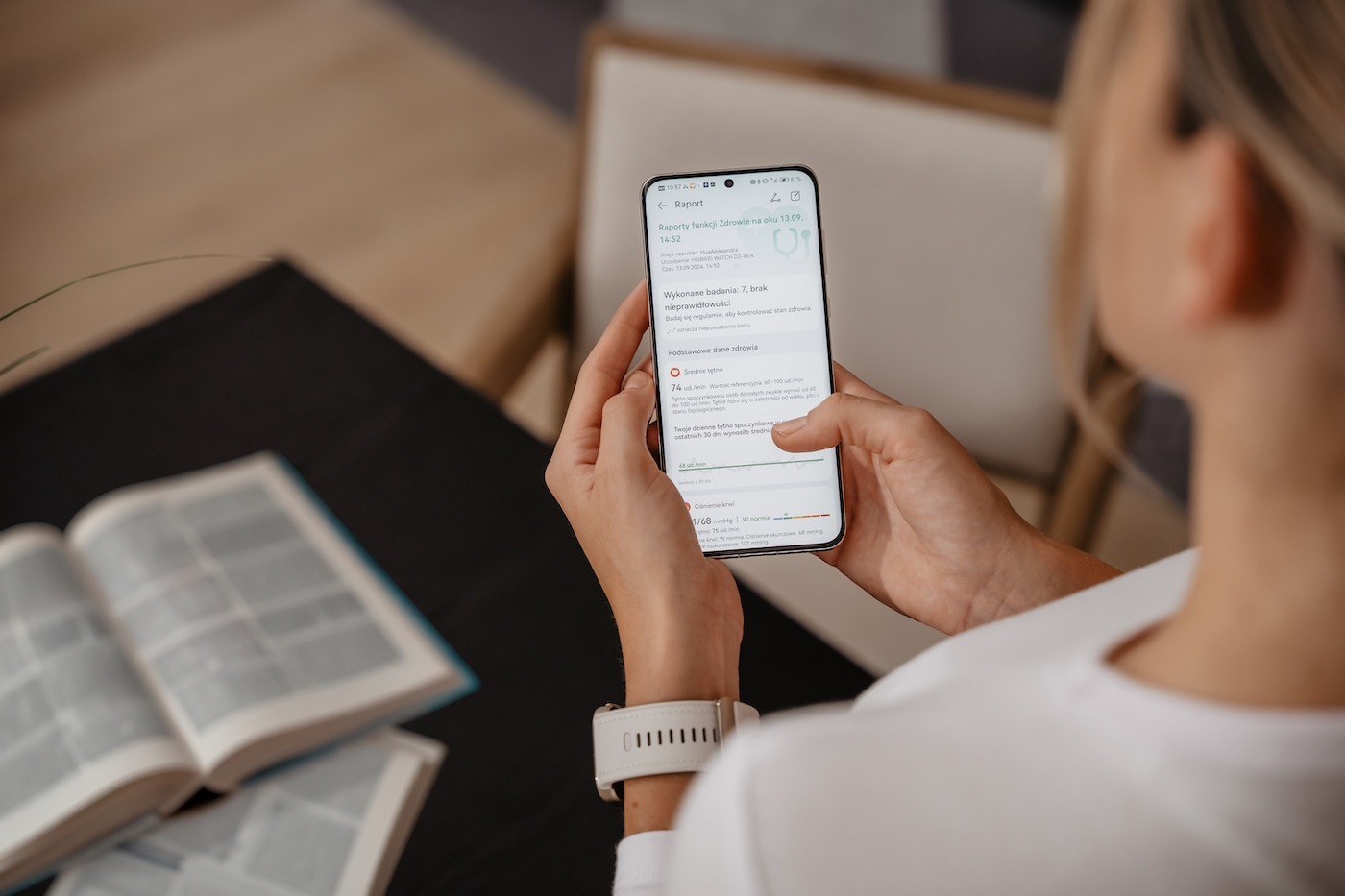 Kobieta trzymająca telefon i używająca zegarka HUAWEI WATCH D2 oraz smartfona do sprawdzania danych dotyczących zdrowia.