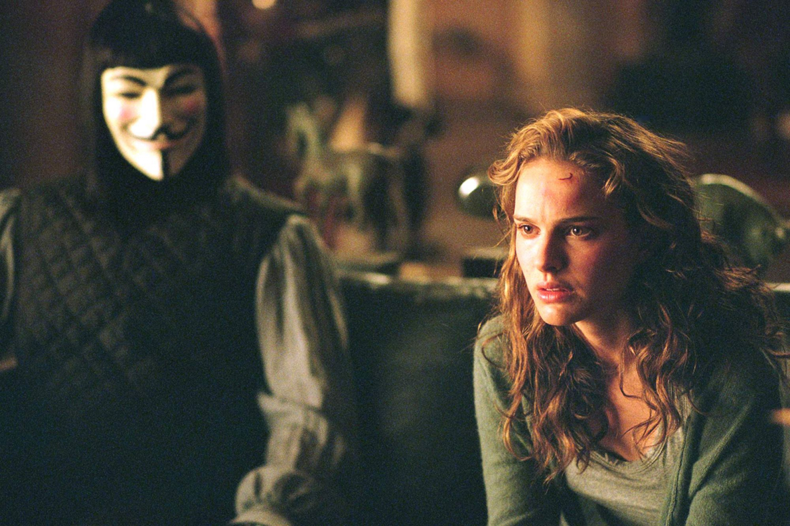 Natalie Portman w filmie „V jak Vendetta” z 2005 roku, siedzi obok postaci w masce.