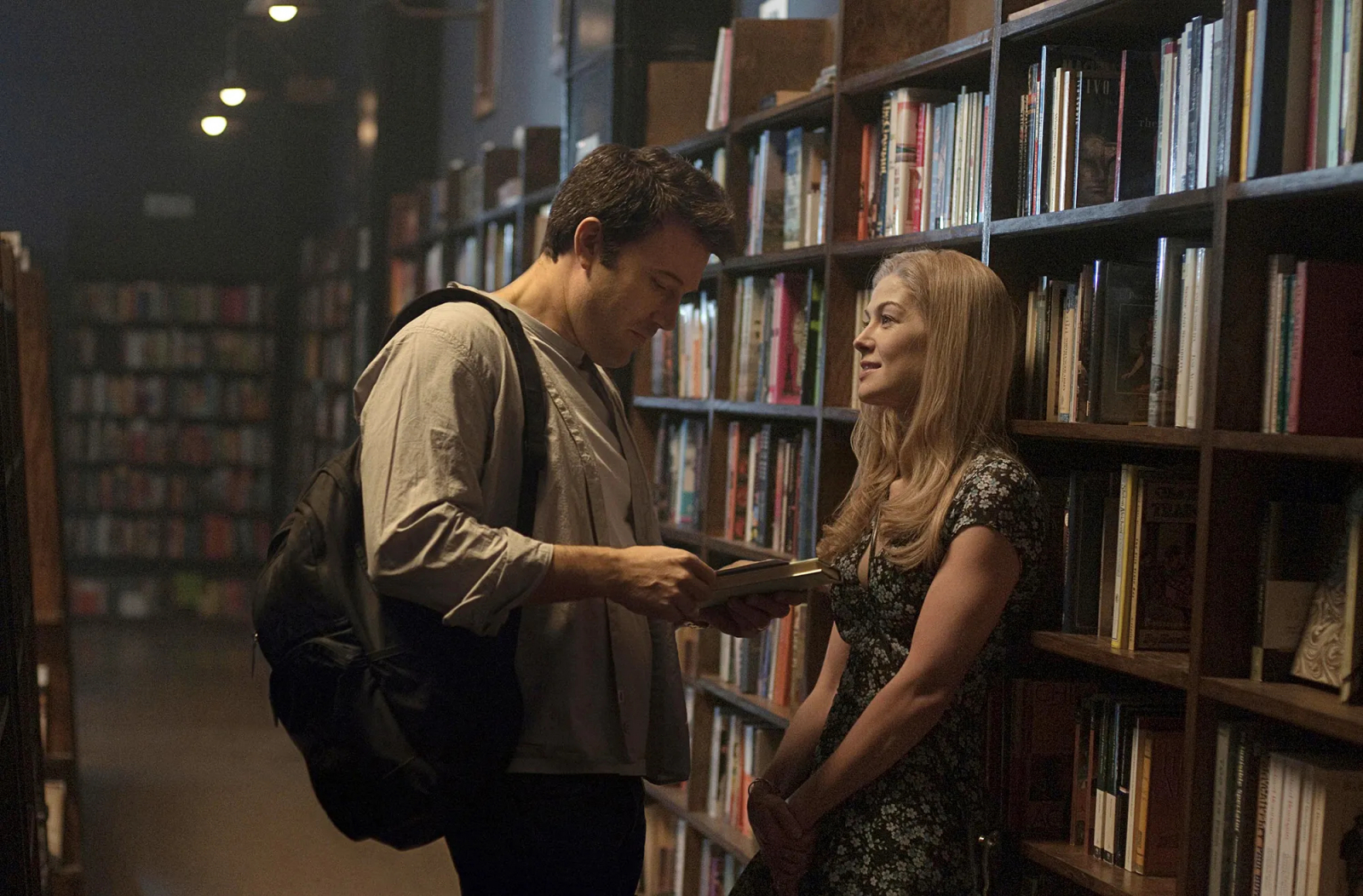 Ben Affleck i Rosamund Pike w scenie z filmu „Zaginiona dziewczyna”, adaptacji książki Gillian Flynn, w bibliotece.