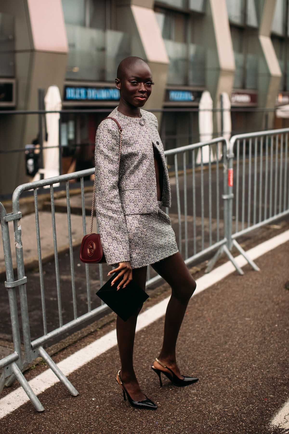 Modelka w eleganckim komplecie z czółenkami typu slingback z łańcuszkiem, pozująca na ulicy.