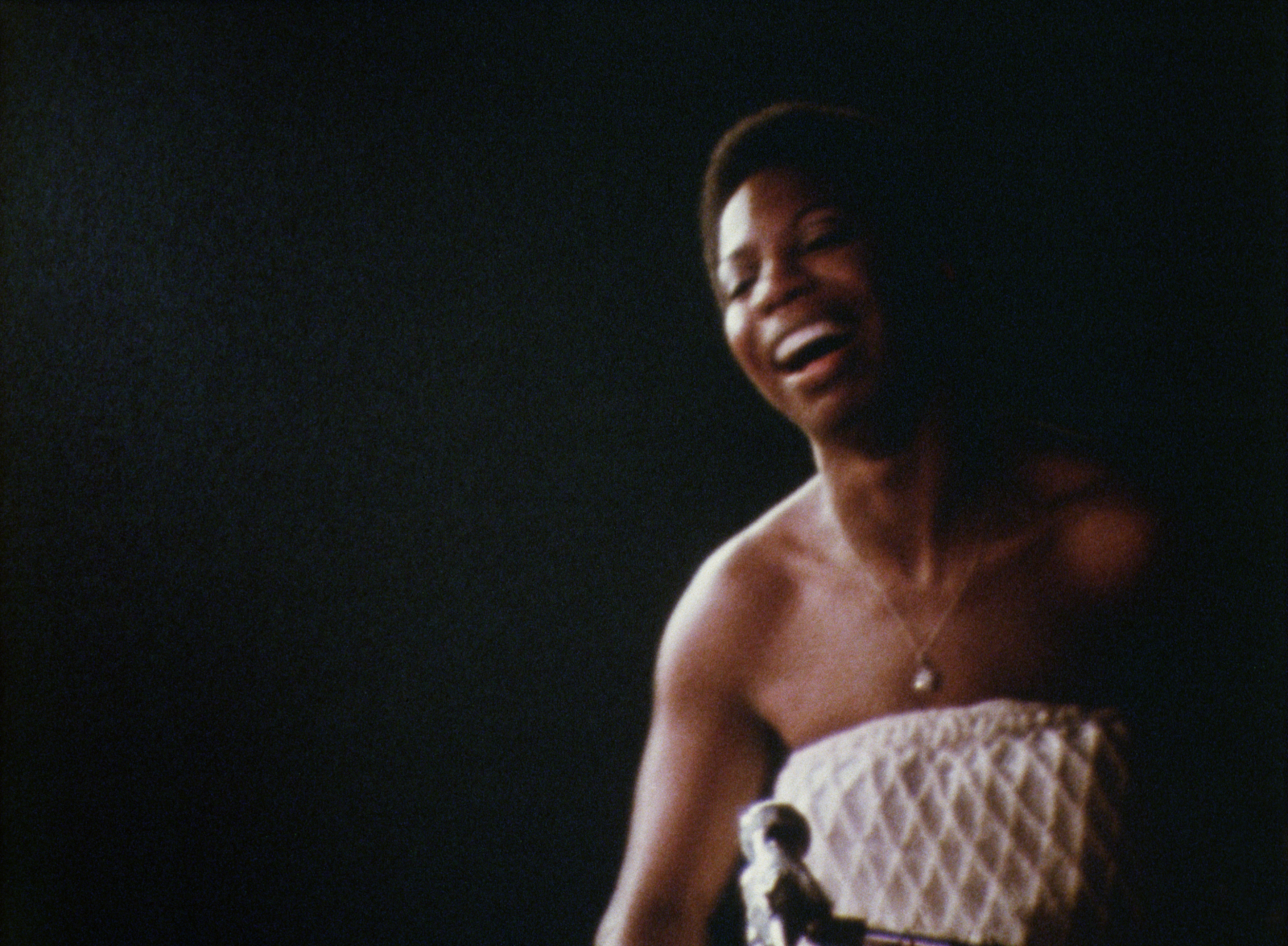 Kadr z filmu dokumentalnego Netflix „What Happened, Miss Simone?” przedstawiający uśmiechającą się artystkę na scenie.