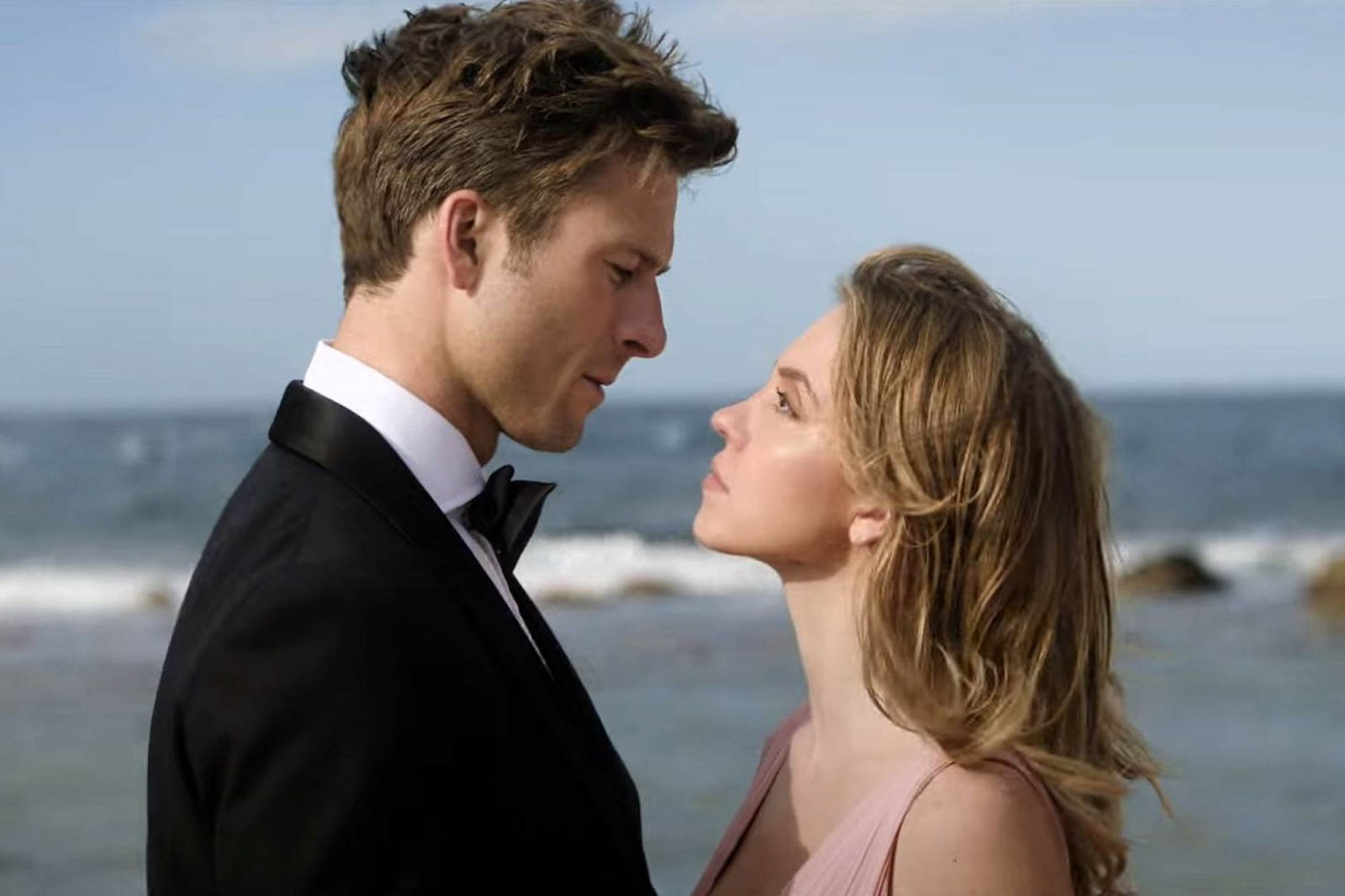 Glen Powell i Sydney Sweeney w romantycznej scenie z dobrej komedii „Tylko nie ty” na tle morza.