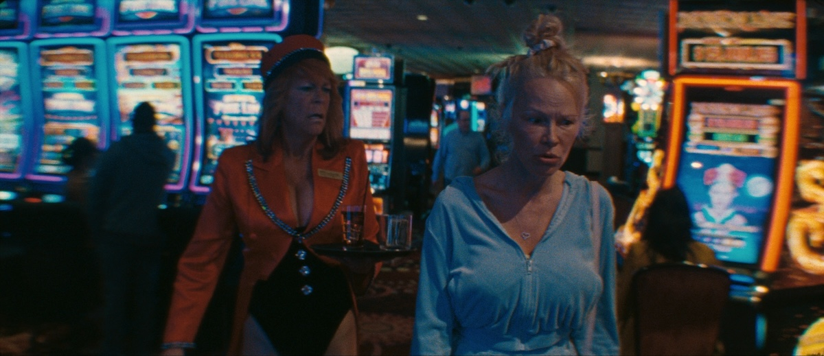 Jamie Lee Curtis i Pamela Anderson w filmie „The Last Showgirl” w kasynie, otoczone automatami do gier.