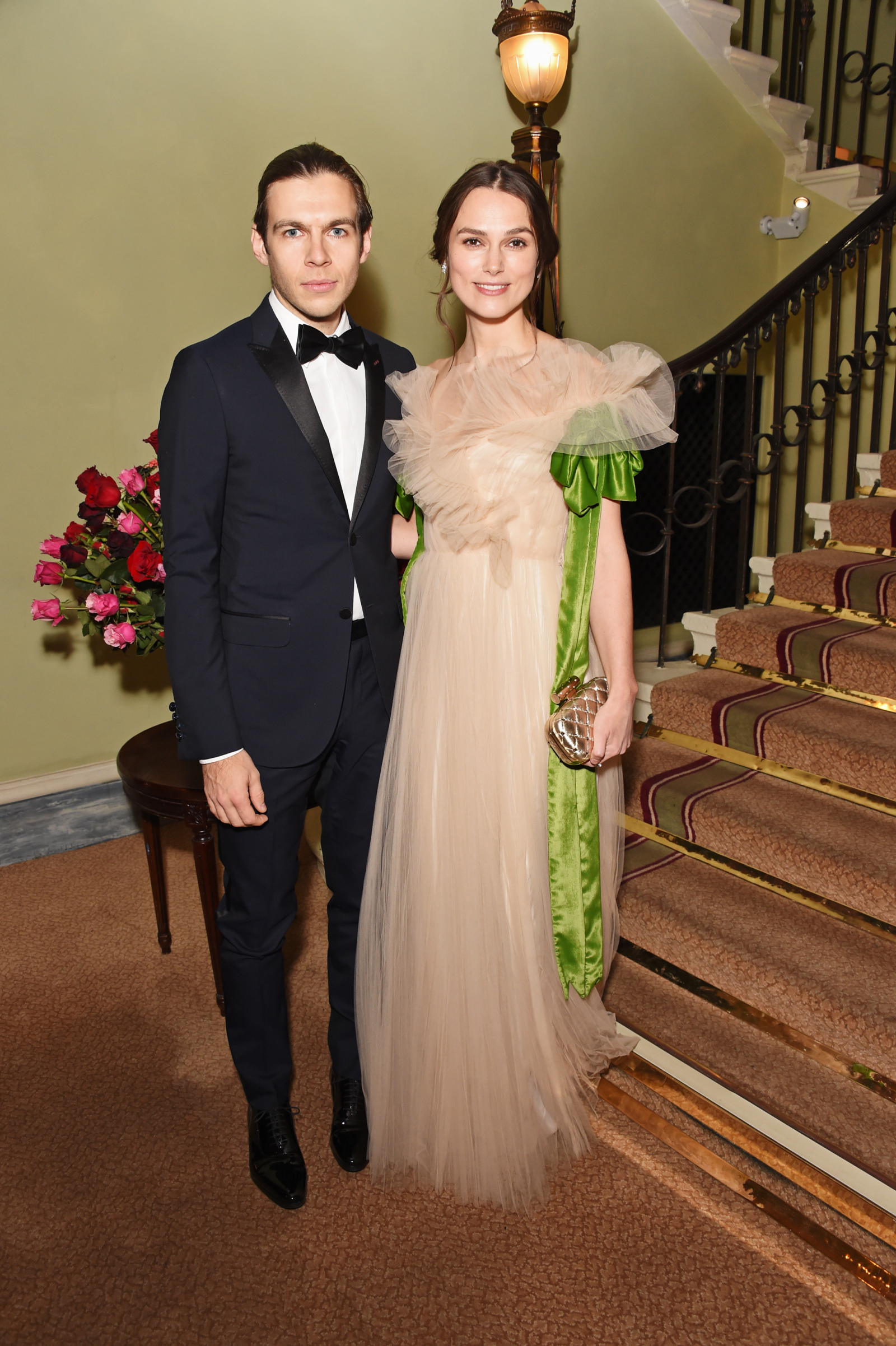 Keira Knightley i James Righton pozują na schodach, otoczeni eleganckim wystrojem.