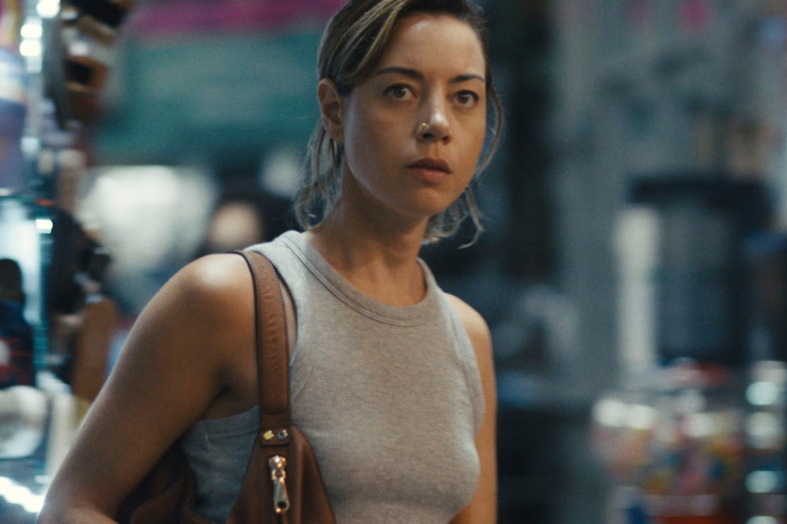 Aubrey Plaza w filmie „Na złej drodze”, wygląda na zaniepokojoną, spacerując przez kolorowy targ.