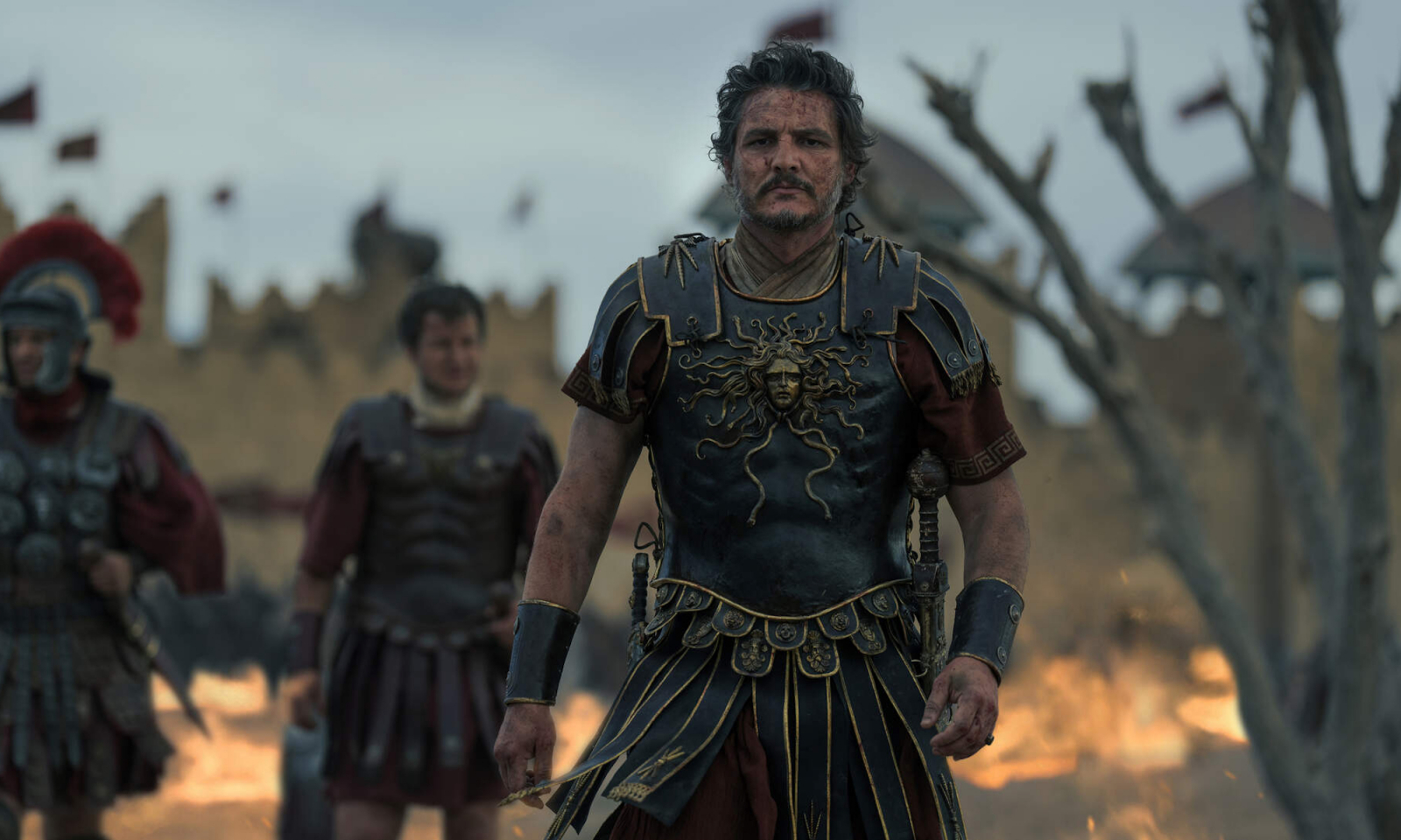 Pedro Pascal jako generał Marcus Acasius w filmie „Gladiator 2”, w zbroi, na tle płonącego pola bitwy.