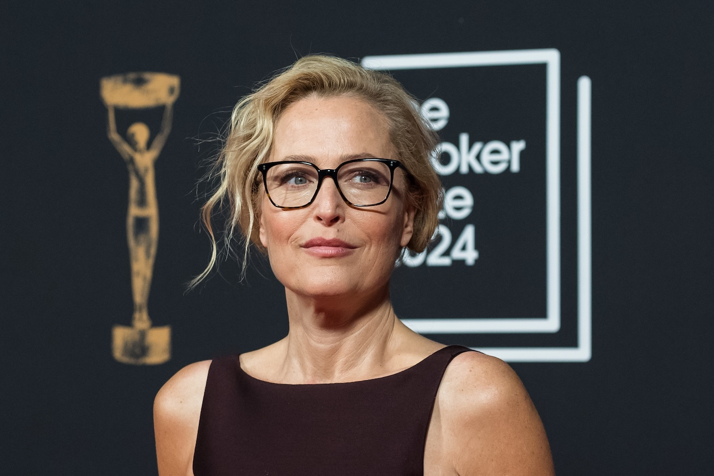 Gillian Anderson na rozdaniu Nagrody Bookera 2024, z charakterystycznymi okularami w czarnej oprawie i elegancką fryzurą.