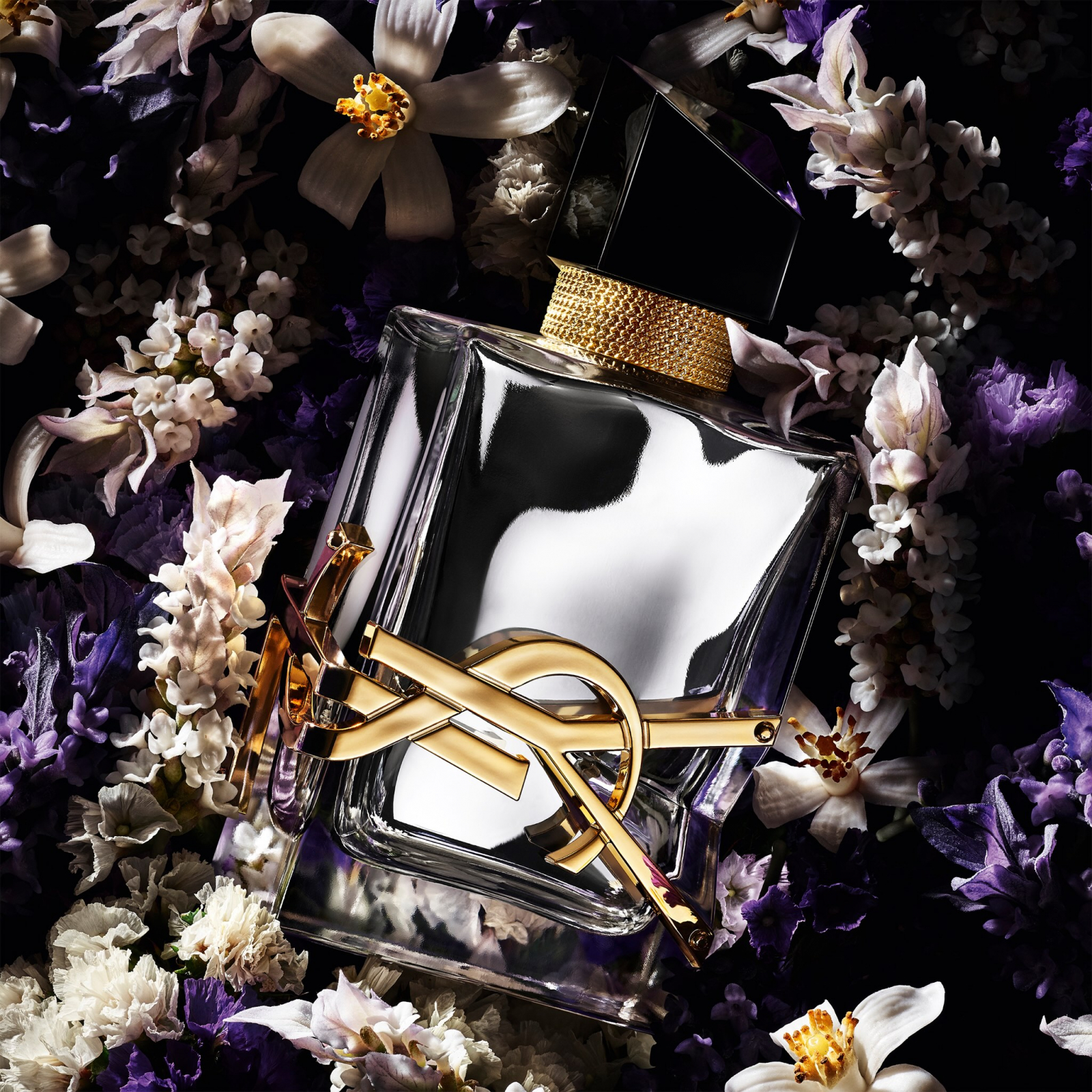 Perfumy Yves Saint Laurent Libre L’Absolu Platine na tle kwiatów.