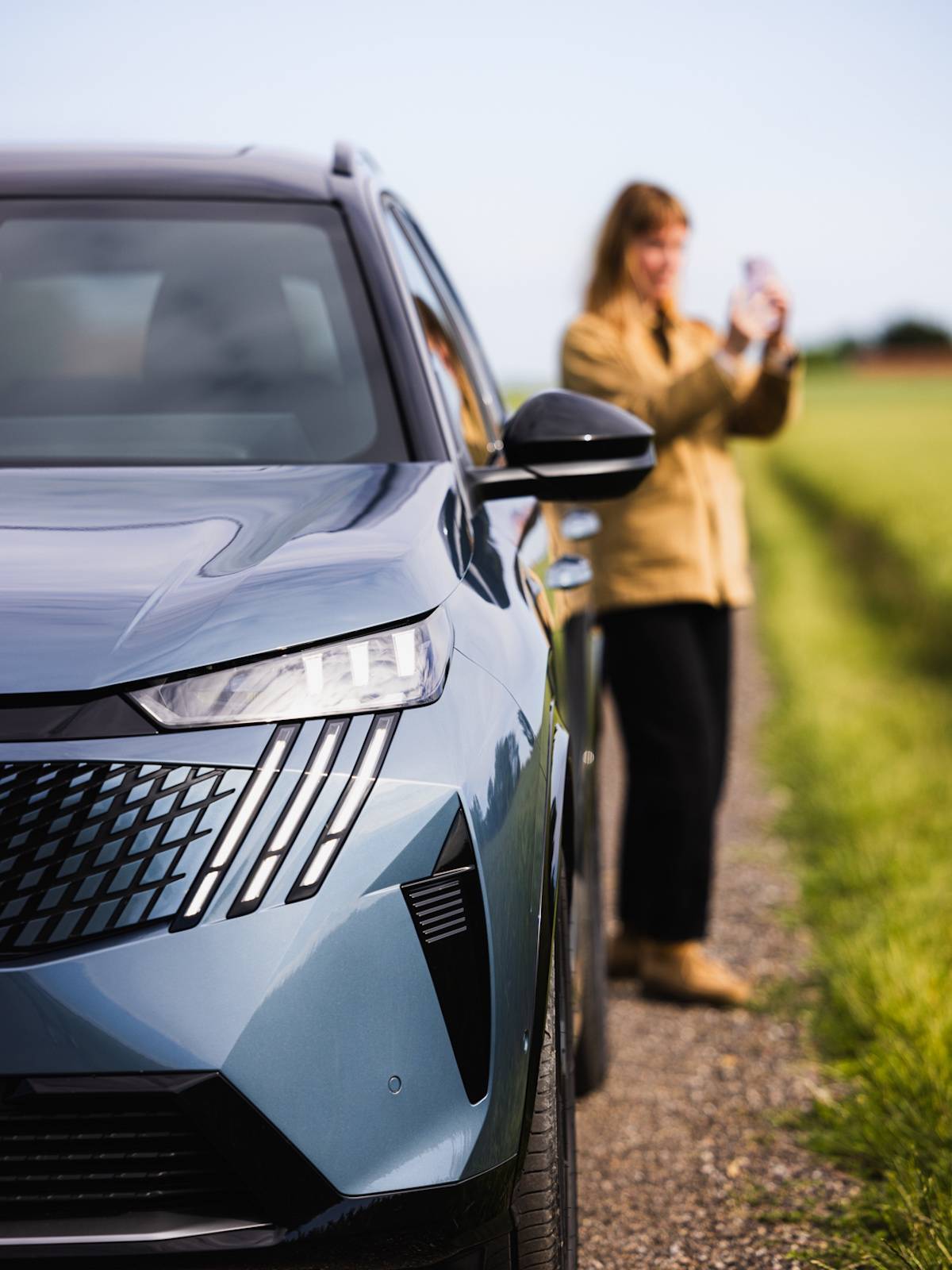 Kobieta robiąca zdjęcie obok samochodu Peugeot E-5008