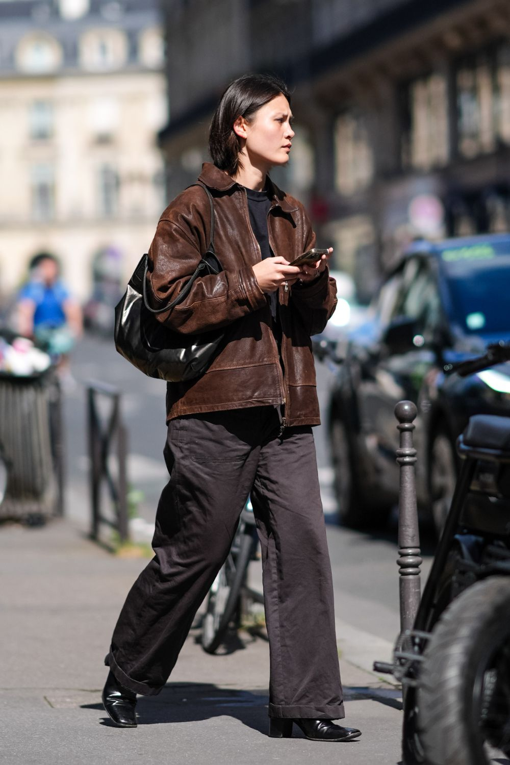 Kobieta w eleganckich botkach damskich oraz luźnych jeansach damskich przechadza się ulicą.